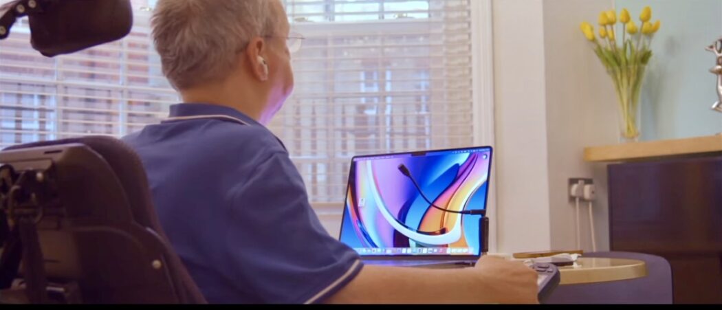 Disabled man in wheelchair dictating at a MacBook laptop with a microphone using Apple voice control