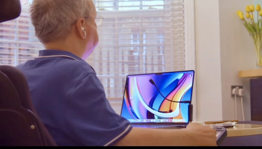 Disabled man in wheelchair dictating at a MacBook laptop with a microphone using Apple voice control