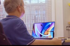 Disabled man in wheelchair dictating at a MacBook laptop with a microphone using Apple voice control