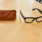 Ray-Ban Meta smart glasses Gen 2 with black frames placed on a wooden table next to a brown Ray-Ban case
