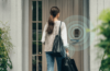 Person approaching a front door with an Aqara smart lock, illustrated with wireless proximity rings to show hands-free unlocking using Ultra Wideband technology.
