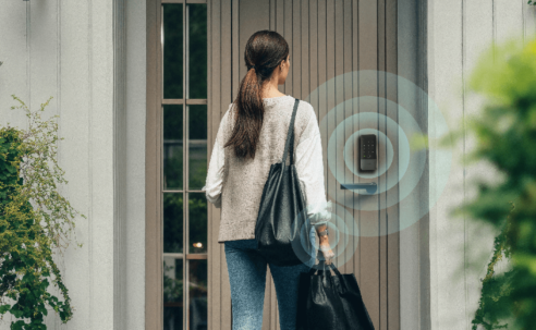 Person approaching a front door with an Aqara smart lock, illustrated with wireless proximity rings to show hands-free unlocking using Ultra Wideband technology.