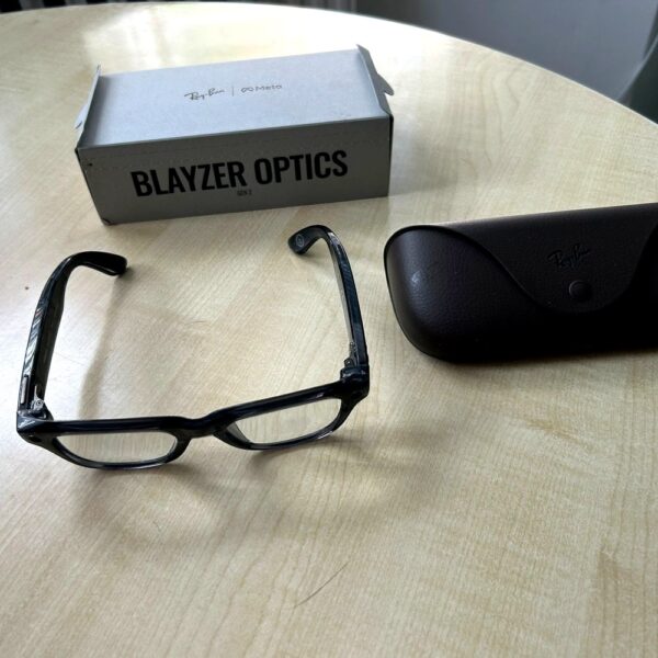 Ray-Ban Meta Blayzer Optics smart glasses on a table with charging case and box for a Ray-Ban Meta Blayzer Optics review.